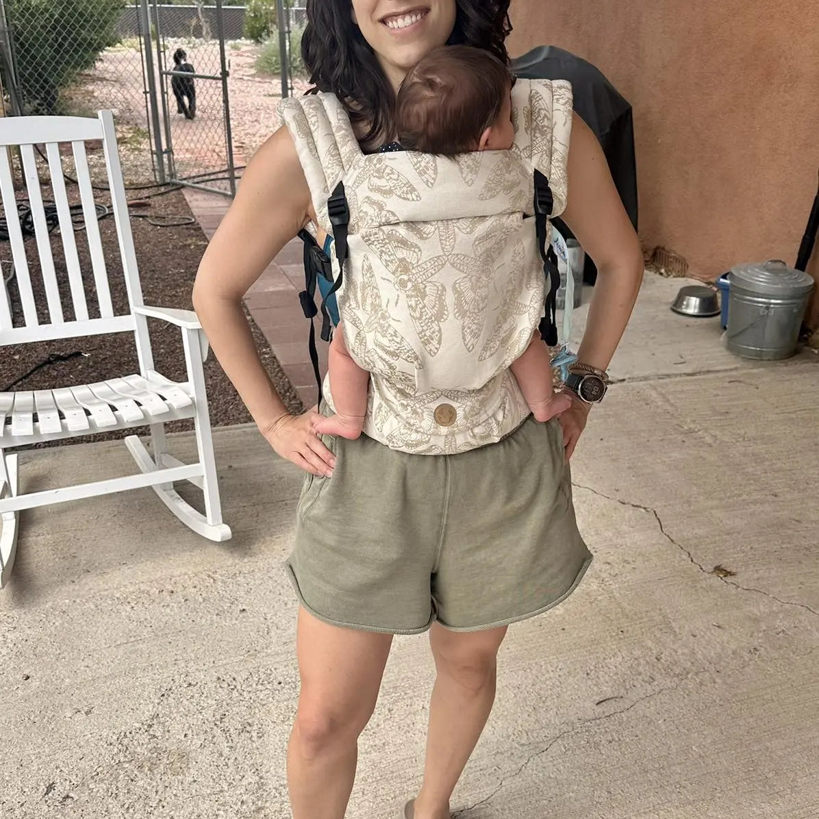 Woman carrying a baby in a lennylight baby carrier (alternative to artipoppe) outdoors on a sunny day.