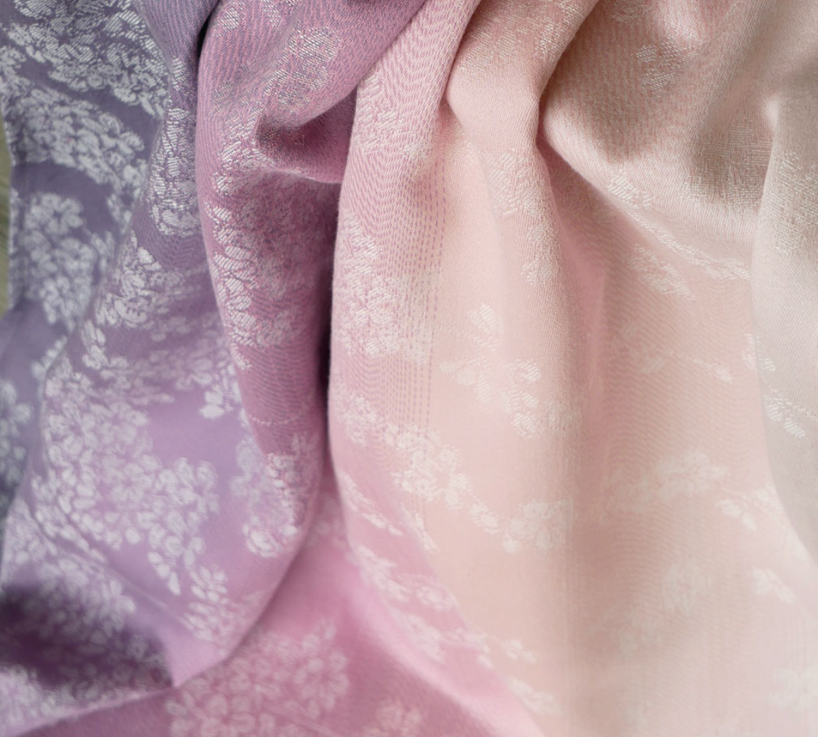 Close-up of textured fabric with a floral pattern in soft purple and pink colors.