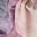 Close-up of textured fabric with a floral pattern in soft purple and pink colors.